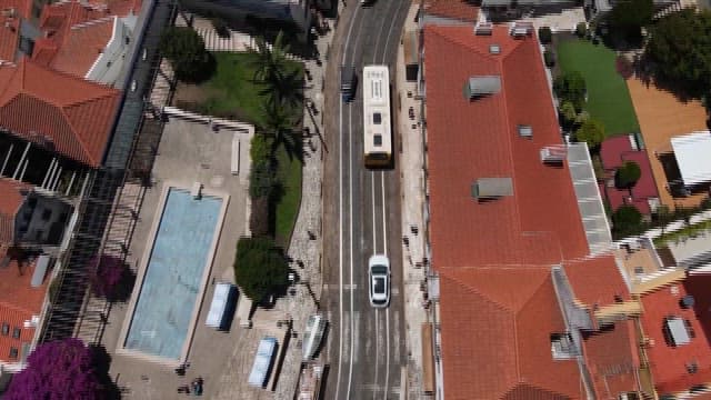 Cars and Bus Passing on the Street Between Red-roofed Buildings