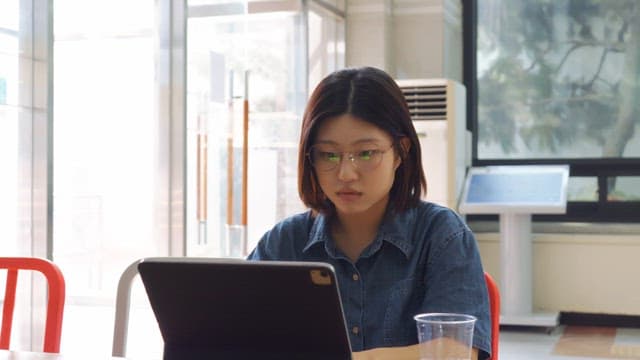 Woman wearing glasses using tablet indoors