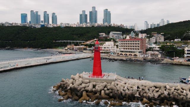 Coastal cityscape with a red lighthouse by the sea