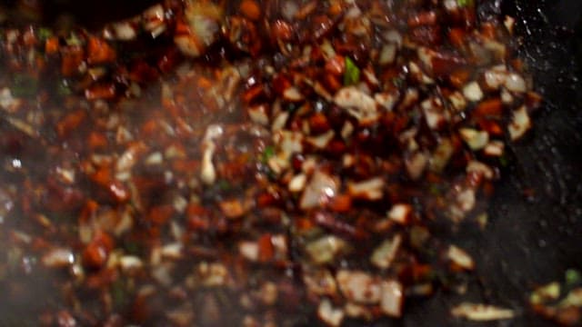 Making Jjajang sauce by stir-frying black bean paste, vegetables, and meat in a wok
