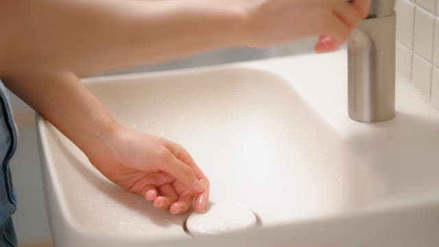 Person washing hands at a sink in a clean bathroom