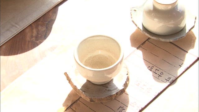 Pouring Green Color Tea Into a Cup on a Sunny Day