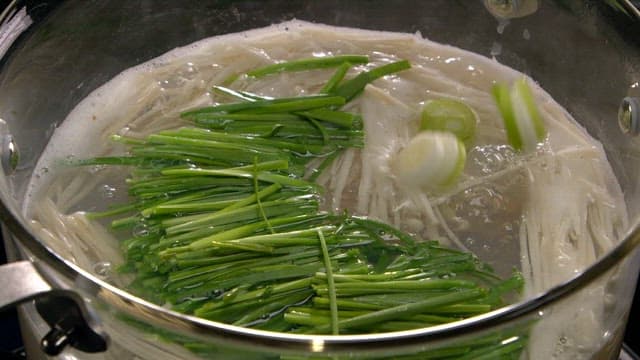 Green onions and mushrooms boiling in a pot