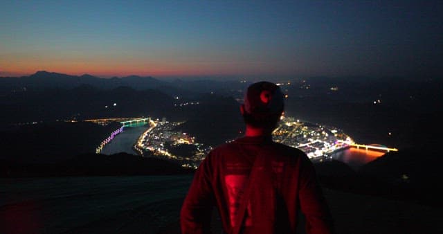 Man overlooking city lights at dusk