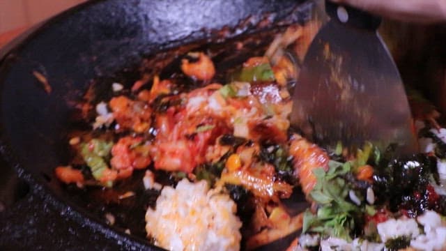 Spicy stir-fried chicken fried rice being cooked in a hot pan