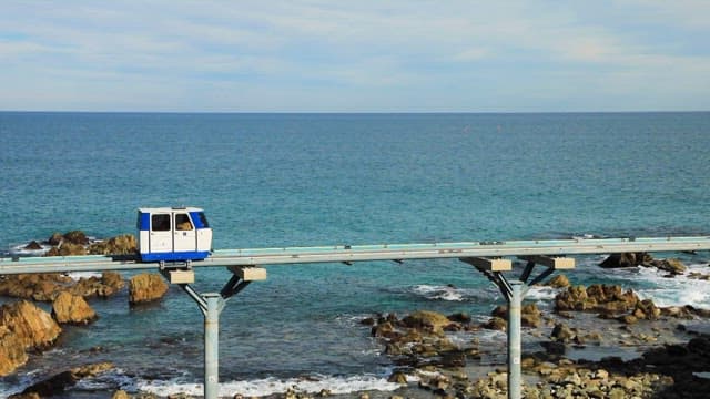 Coastal Monorail above the Rocky Shoreline with Waves on a Clear Day