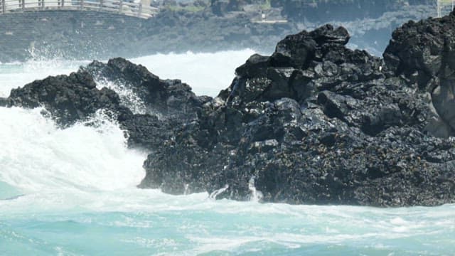 Waves crashing against black rocks