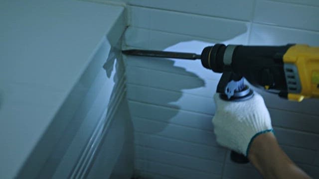 Worker Removing Bathtub with Power Drill
