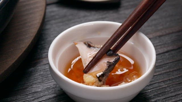 Bite of Conch Dipped in Oil Sauce