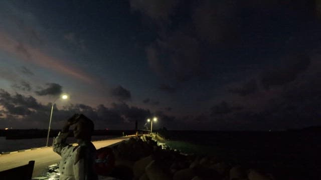 Seascape from night to morning from a quiet pier with a breakwater