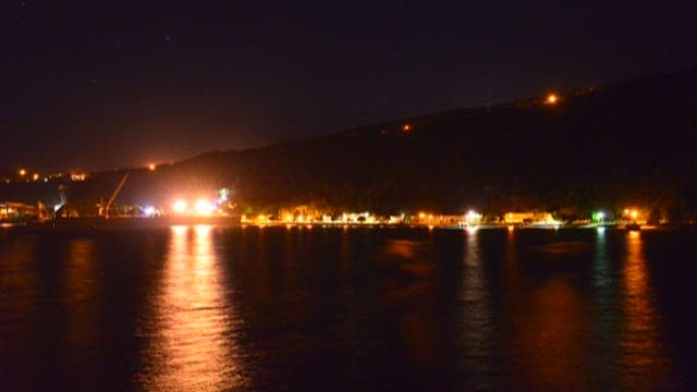 Sea illuminated by the lights of a coastal town