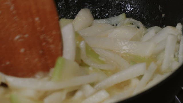 Shredded radish being stir-fried in a frying pan