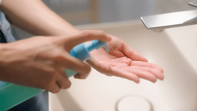 Woman applying cleansing oil to her hands in bathroom