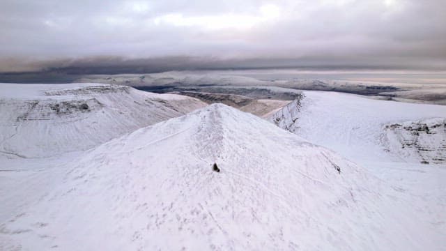 Snow-covered mountain range under cloudy sky