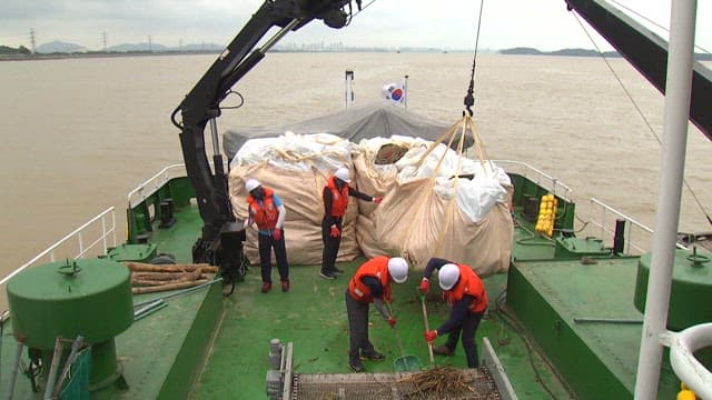 Workers on a ship clearing debris under cloudy weather
