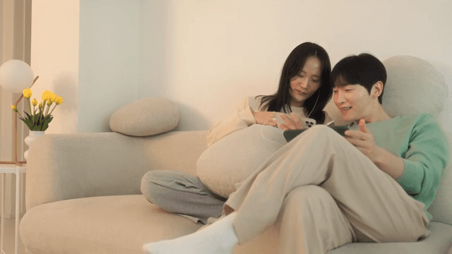Two people using digital devices on a sofa in cozy living room
