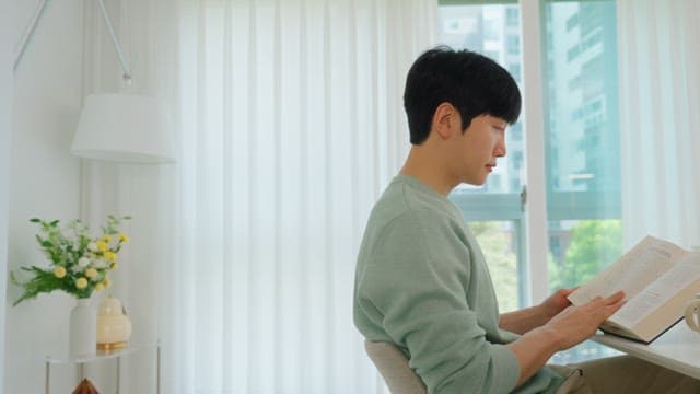 Man Reading a Book by the Window in Bright Living Room