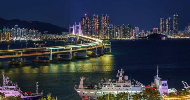 Night view of a bustling port city Busan with tall skyscrapers and Gwangan Bridge