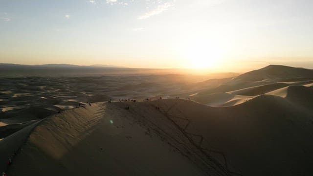People on sand dunes at sunset