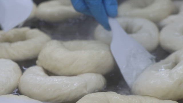 Boiling bagels being stirred by a spatula