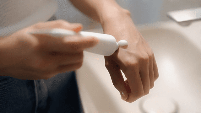 Woman applying lotion on her hand in the bathroom.