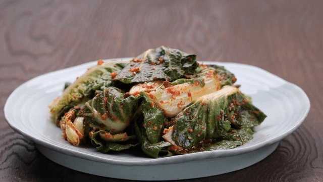 Plate of fresh kimchi made with spring cabbage on a wooden table
