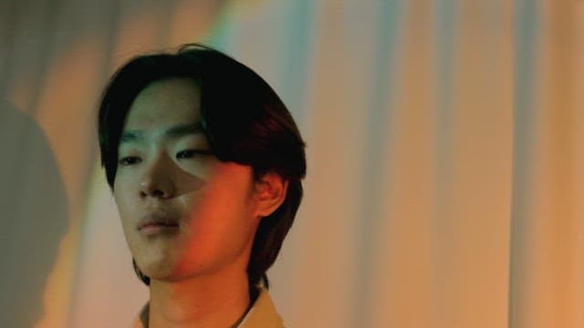 Man holding back laughter in colorful lighting