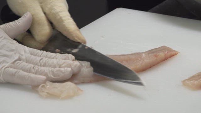 Cutting raw fish with a knife on a kitchen cutting board