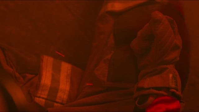 Firefighter Wearing Gloves and Holding Candle in Hand at Fire Scene