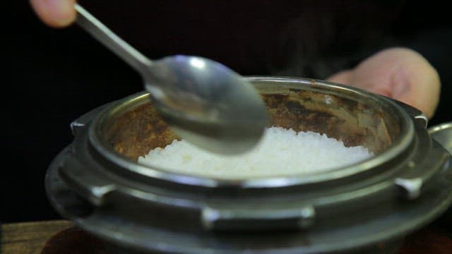 Steaming rice being served from a pot
