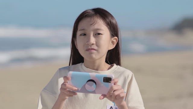 Girl holding a cell phone runs into the sea