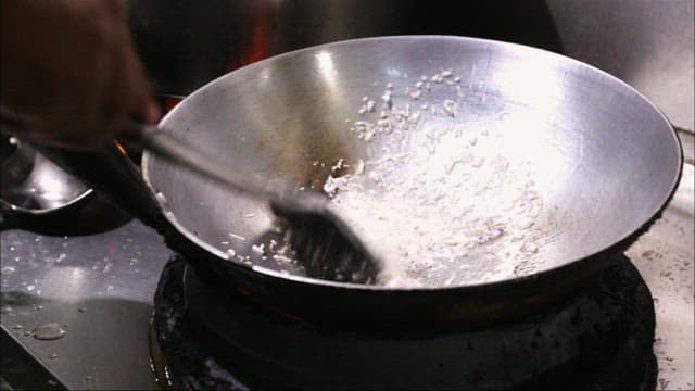 Cooking with a hot wok in a restaurant kitchen