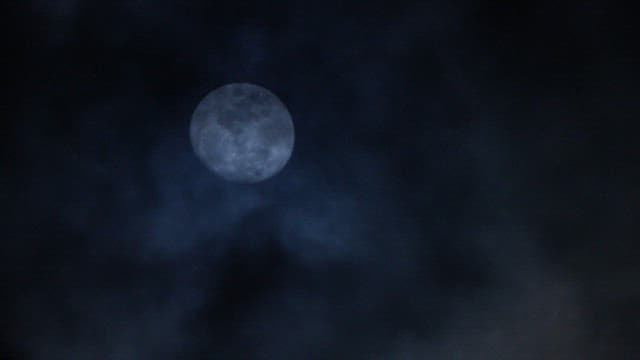Full moon in a cloudy night sky