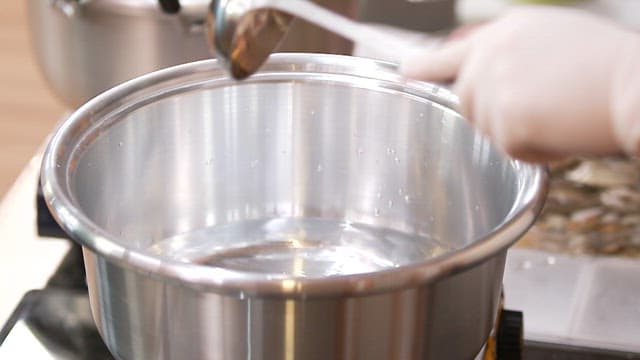 Adding mussels to a pot of water in an indoor kitchen