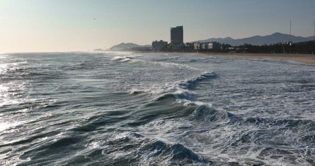 Serene Beachfront with Crashing Waves and Buildings