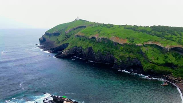 Coastal cliffs with green hills and a lighthouse