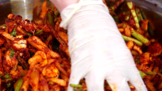 Mixing kimchi ingredients with gloved hands