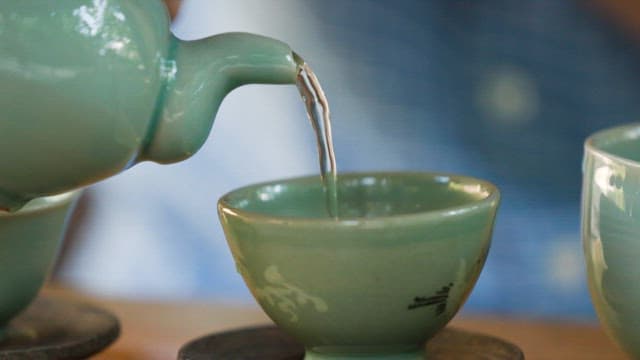 Pouring tea into a green ceramic cup