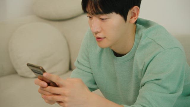 Man seating on a couch using a smartphone