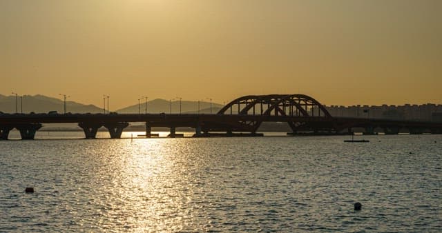Busy traffic on a bridge with lights on under a sunset sky in the evening