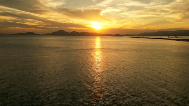 Sunset over a calm sea with distant mountains