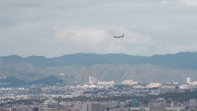 Airplane flying over a cityscape with mountains