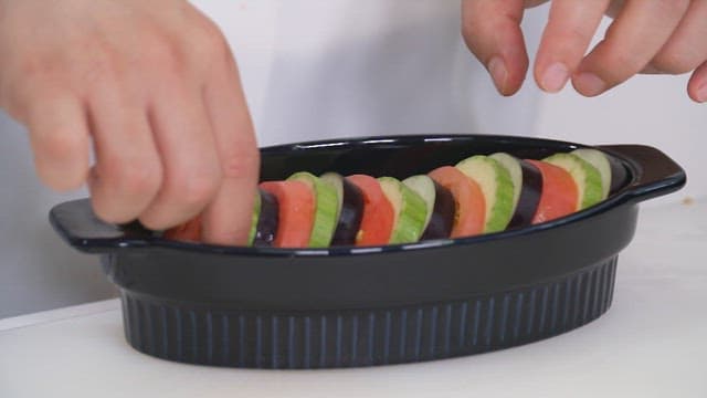Tomatoes, zucchini and eggplant in a black oven dish in the kitchen