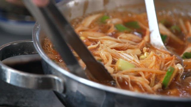 Close-up of a simmering pot of spicy stew with vegetables and abalone