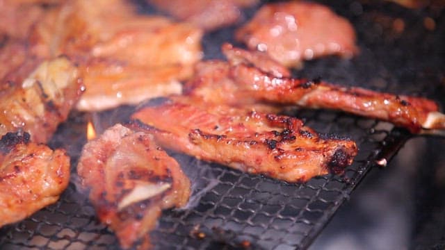 Grilling marinated pork ribs on a grill over burning charcoal
