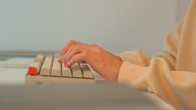 Woman using a keyboard at a desk in a calmly lit room