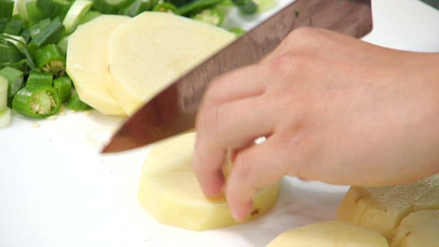 Cutting potatoes with a knife on a cutting board