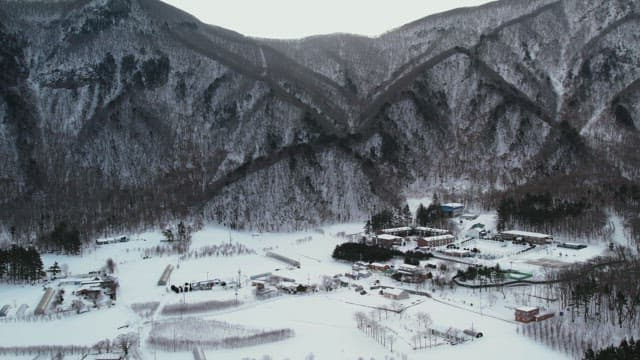 Snow-Covered Village Under Lush Snowy Mountains