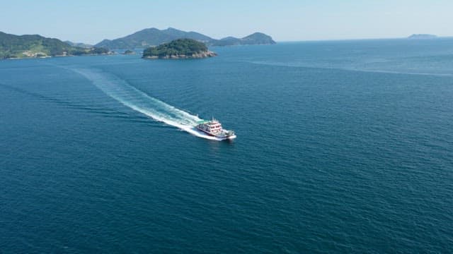 Ferry cruising in a vast ocean surrounded by islands under a clear sky