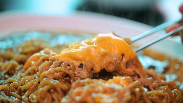 Cheese blackbean ramyeon being lifted with chopsticks